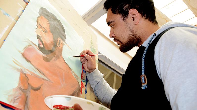 A UCOL learner working on a self potrait on a canvas