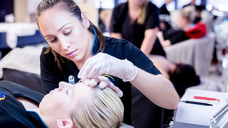 A UCOL beauty student working on the eyebrow of a client.