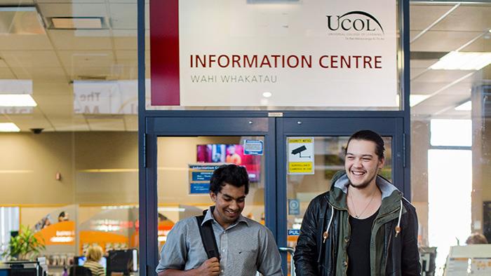 Two people walking together near UCOL's Information Centre