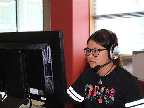 A lady studying at a computer wearing a headset