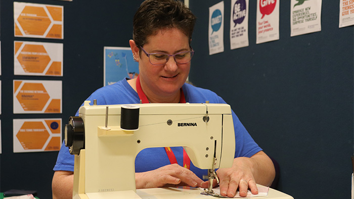 Angie Crabtree using a sewing machine to make a mask