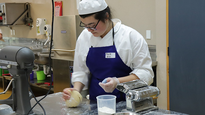 student kneading dough