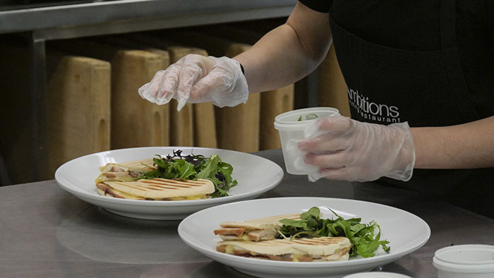 A student plating panini dishes