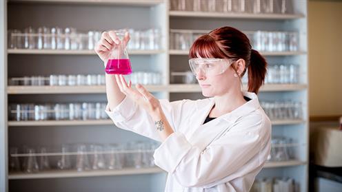 A photograph of a scientist examining liquid in a beaker in a lab at UCOL.