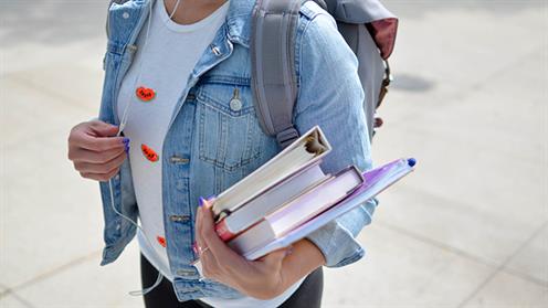 A close up photograph of a student carrying some books