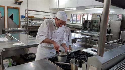 A chef cooking a dish in a commercial kitchen