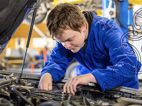 A photograph of two young people looking under the bonnet of a car in an automotive workshop at UCOL