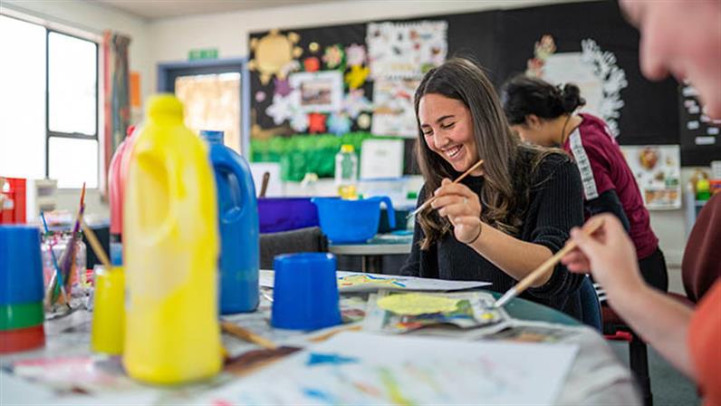 A photograph of a UCOL | Te Pūkenga student attending the early childhood class where she is enjoying painting