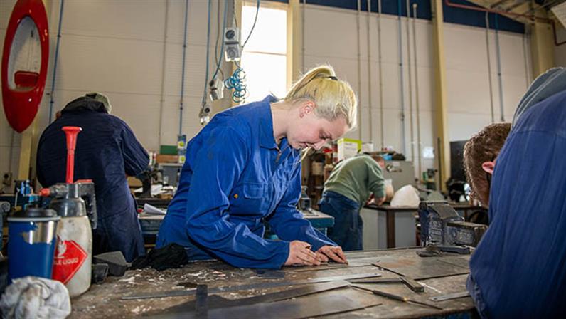 A photograph of a female UCOL student working at the workshop