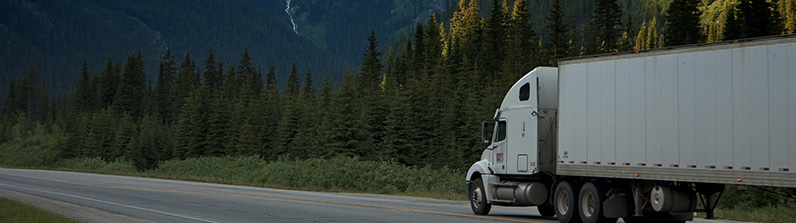 A commercial truck on a highway with mountains in the background