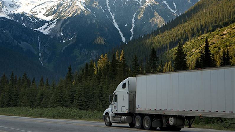 A heavy truck on road with mountains at the background.