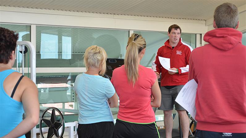 A photograph of UCOL lecturer Hayden Pritchard talking to a group of people in a gym.