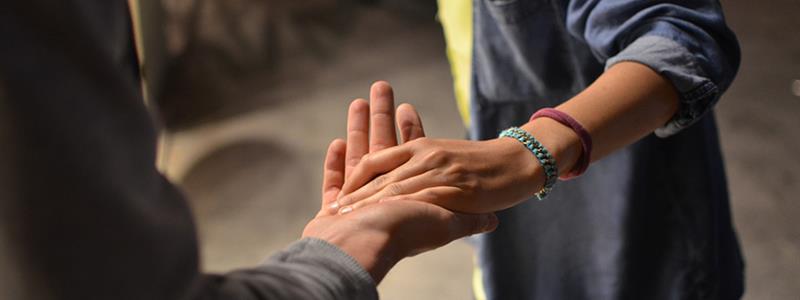 A close-up photograph of a person holding another's hand.