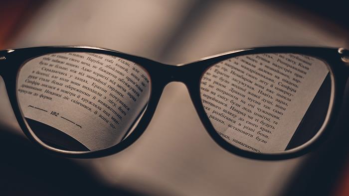 A close up photograph of a book viewed through reading glasses