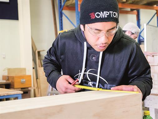 A photograph of a young Maori man doing carpentry