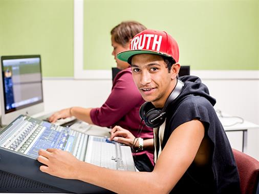 A photograph of a young Maori man at a computer