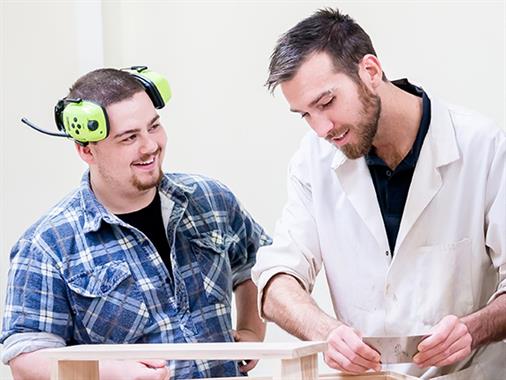 A photograph of a lecturer and a student wearing ear muffs
