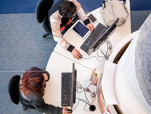 An aerial view of some people using computers at a desk
