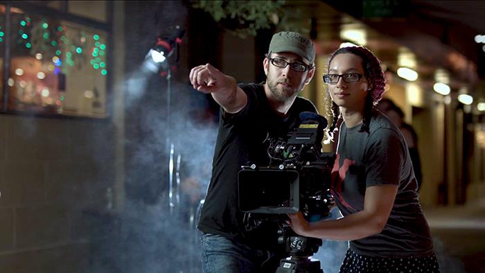 Two people on set of a movie behind the camera lense