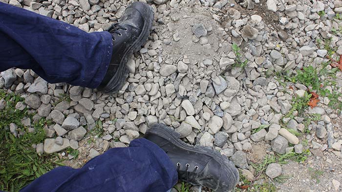 Closeup of a student's work boots on gravel
