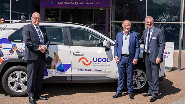 Three people standing infront of a UCOL branded vehicle
