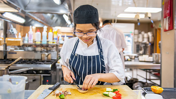 A student chef chopping vegetables