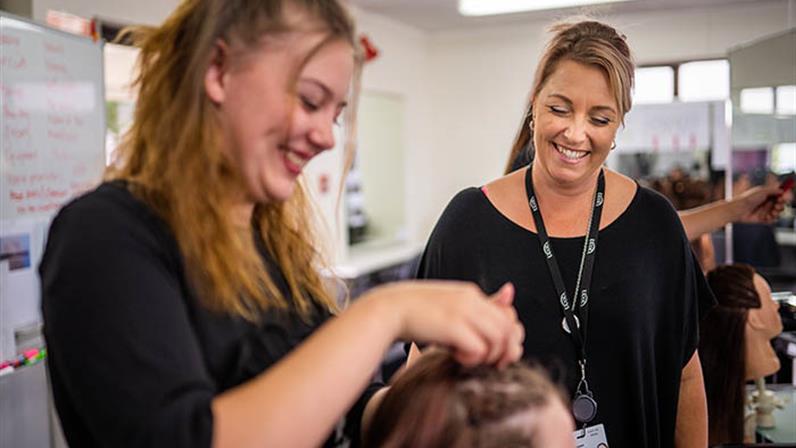 A photograph of a UCOL | Te Pūkenga student dressing a client's hair at one of UCOL's hair saloon
