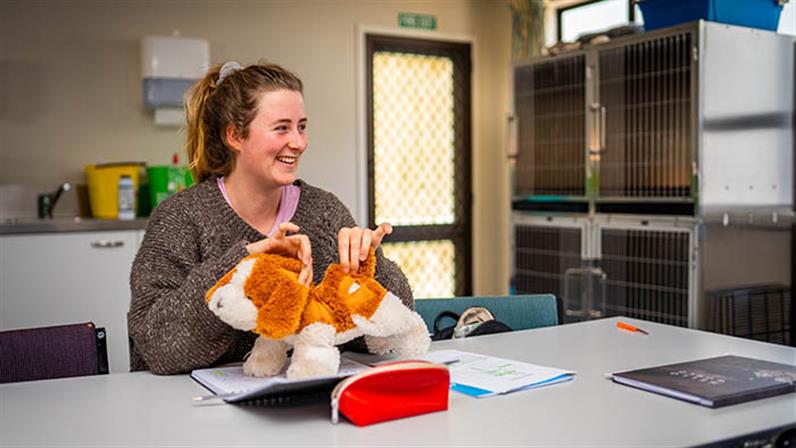 A photograph of a student holding a stuffed puppy