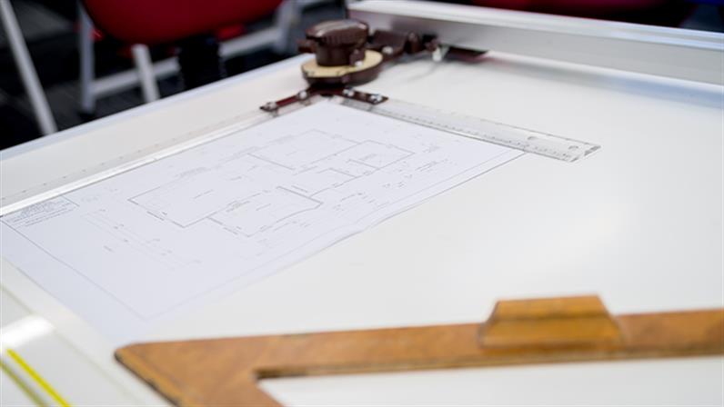 A close-up photograph of architectural drawings on a desk.