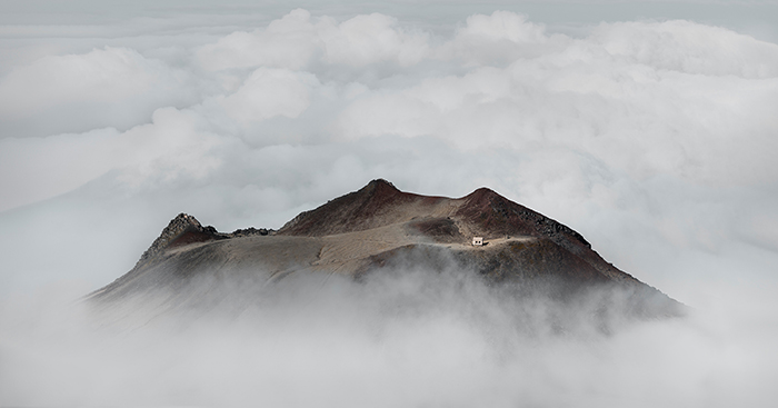 aerial mountaintop with hut surrounded by cloud