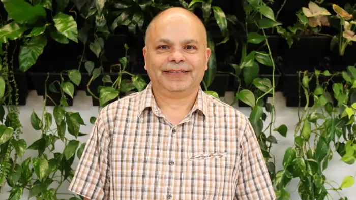 a man smiling in front of a plant