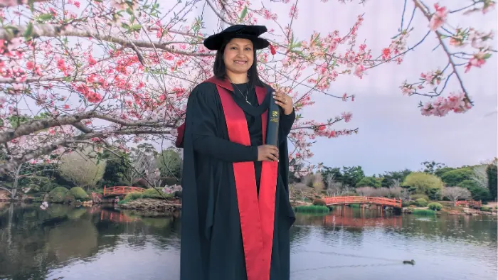 a woman in a black gown and cap holding a diploma