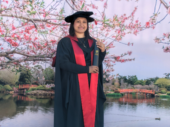 a woman in a black gown and cap holding a diploma