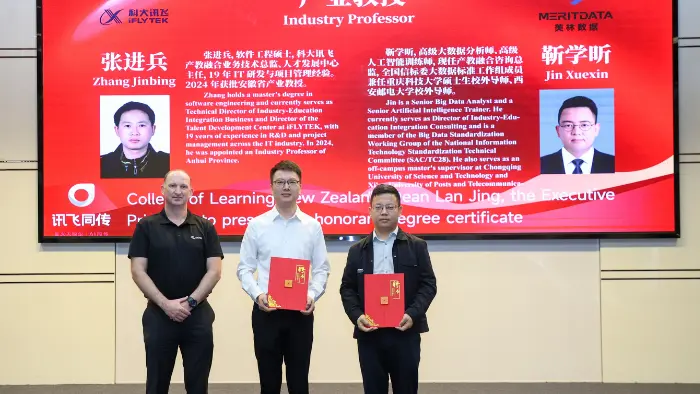 a group of men holding red folders in front of a large screen
