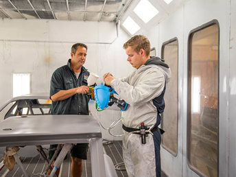 A UCOL lecturer showing a student how to mix paint in a paint booth at UCOL Te Pūkenga paint and panel workshop