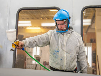 A UCOL student in protective gears painting a car