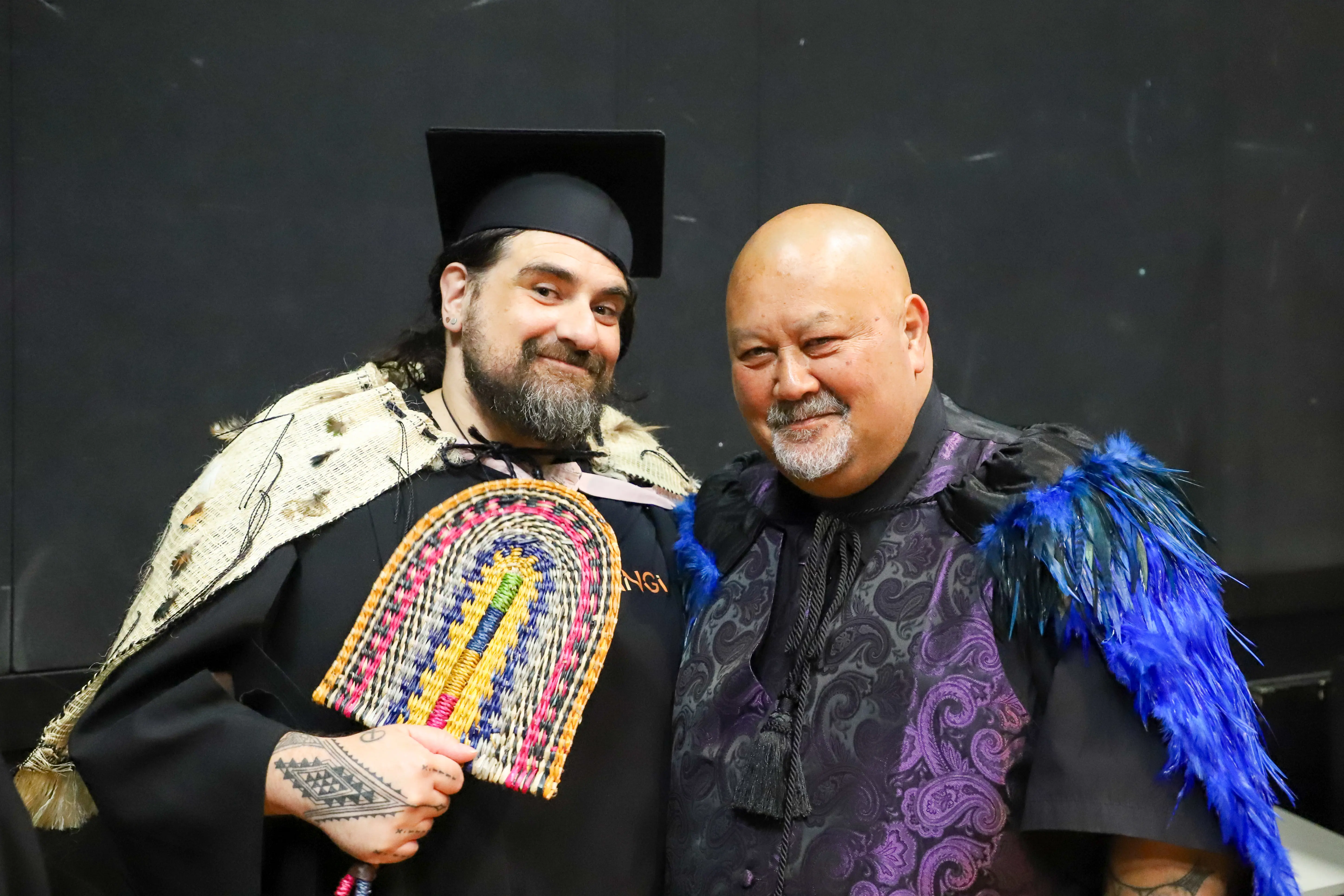 two men in graduation gowns and cap and gowns