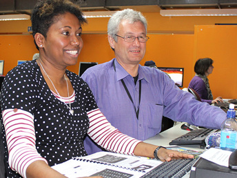 A lecturer instructing a lady at the computer lab
